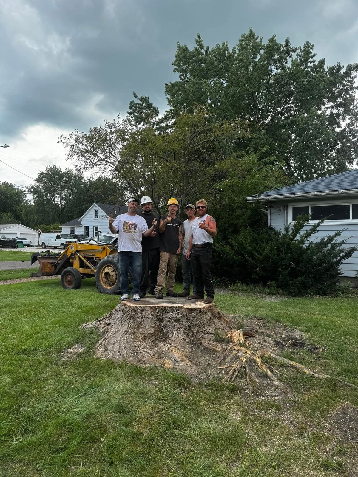 The Thurman & Son Tree Service crew standing on a giant stump after a large tree removal